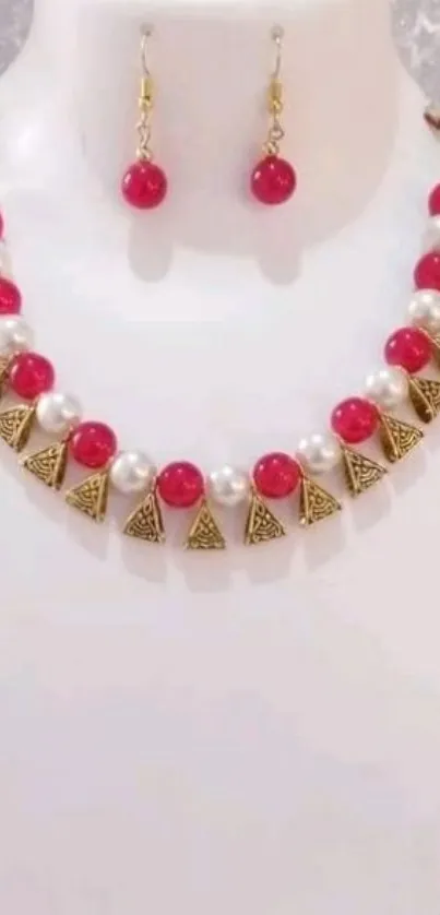 Elegant jewelry set with red beads and pearl accents on white background.