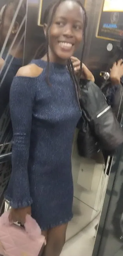 Stylish woman in blue dress standing in an elevator smiling.