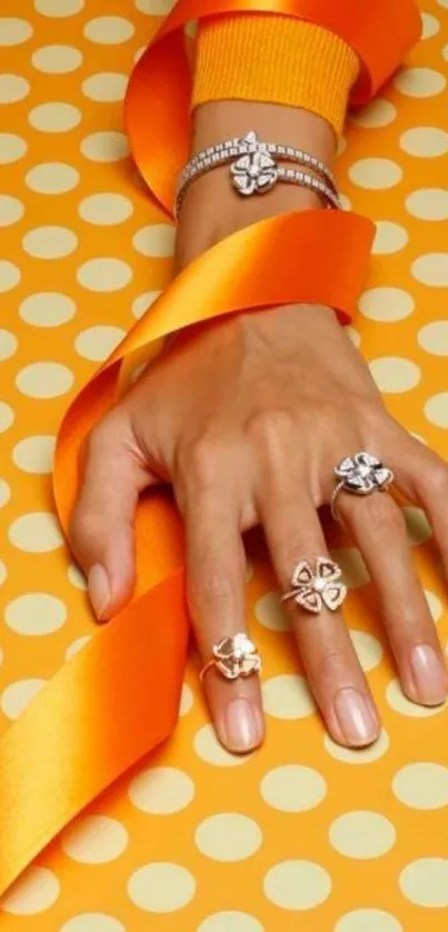 Elegant hand with rings and orange ribbon on polka dots.