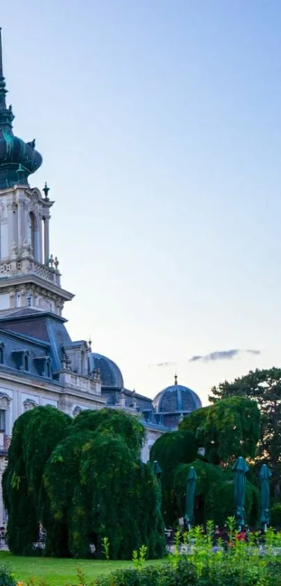 Elegant European palace with lush garden, set against a blue sky.