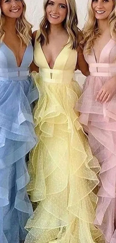 Three friends in pastel gowns, smiling and posing.