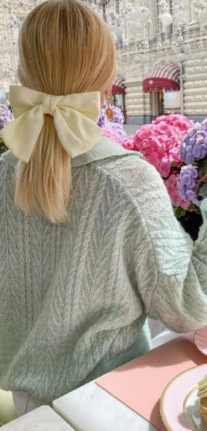 Woman in mint sweater with bow in a chic outdoor setting with hydrangeas.