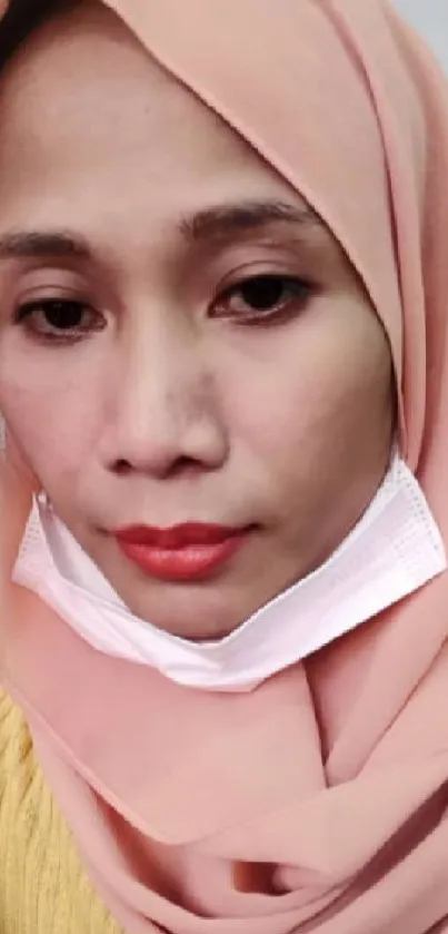 Serene woman in peach hijab with soft tones.