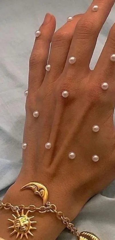 Hand with pearls and golden bracelet on soft fabric.