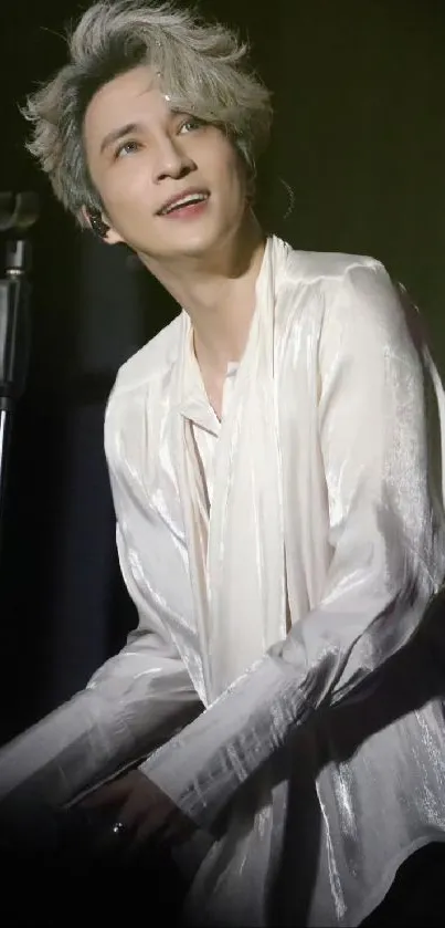 Elegant performer in white shirt on stage.