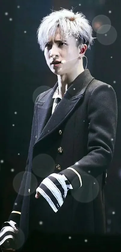 Elegant performer on stage in a black coat, exuding captivating presence.