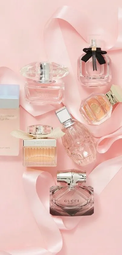 Assorted elegant perfume bottles on a pink background with ribbons