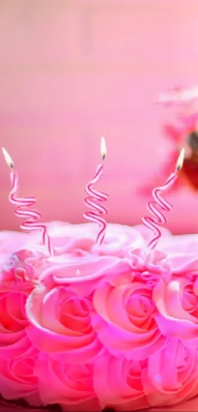 Pink cake with curly candles and vibrant flowers.