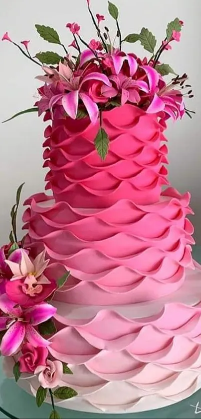 Pink layered cake with vibrant floral decorations.