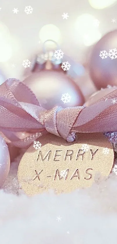 Soft pink Christmas ornaments on snow with 'Merry X-Mas' tag.