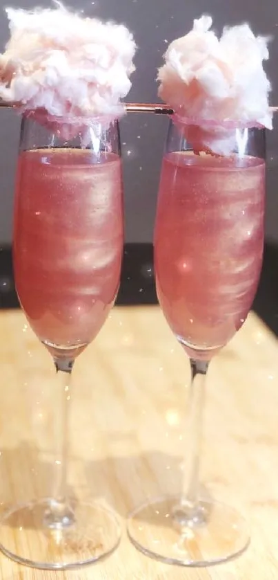 Elegant pink cocktail with cotton candy topping in champagne glasses.