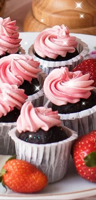 Pink cake and cupcakes with floral decor on a table setting.
