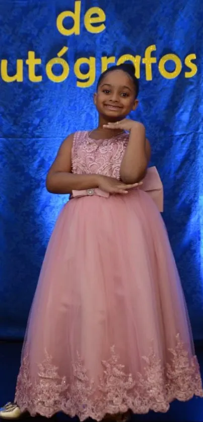 Portrait of a young girl in a pink dress with a blue background.