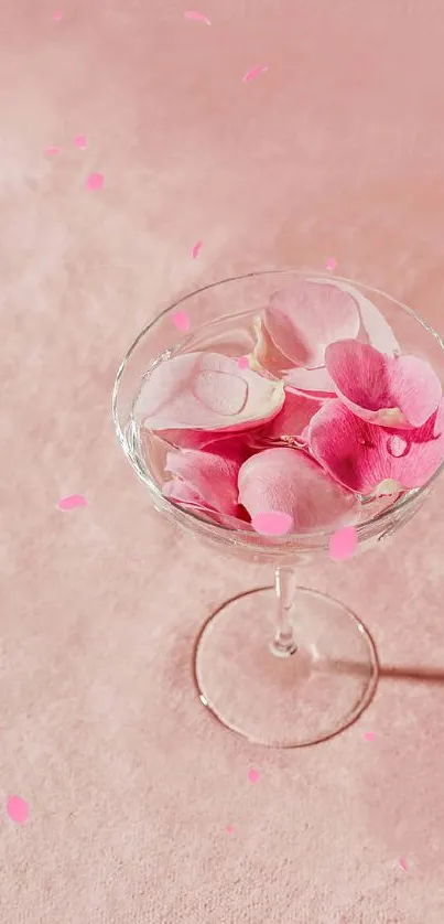 Glass with pink flower petals on a soft pink background.