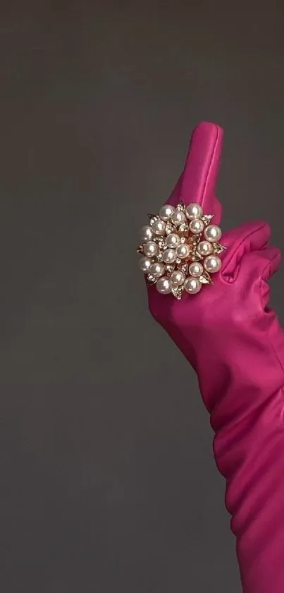 Elegant pink glove with pearl ring on gray background.