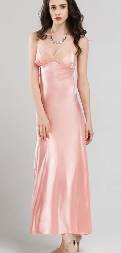 Woman in elegant pink satin dress standing gracefully.