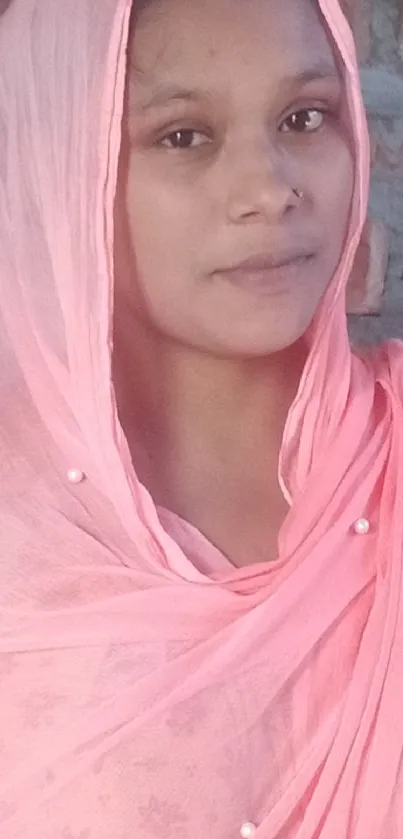 Woman wearing a soft pink scarf in an elegant pose.