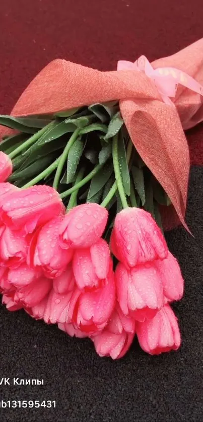 Bright pink tulips wrapped elegantly in a bouquet with dew droplets.