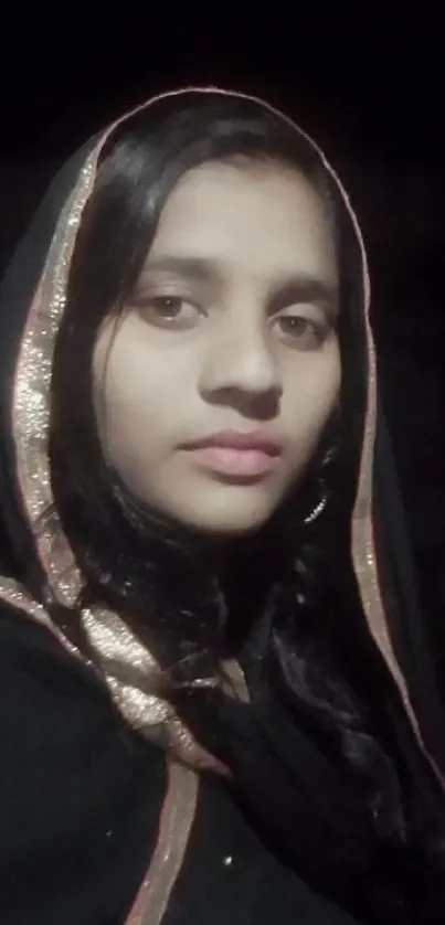 Elegant woman in traditional attire with a black hood and soft lighting.