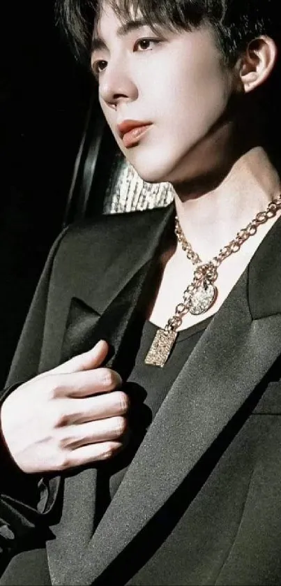 Elegant portrait of a person in a stylish suit with a gold chain necklace.