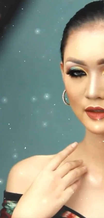 Elegant portrait of a woman with vibrant makeup against a sparkly teal backdrop.