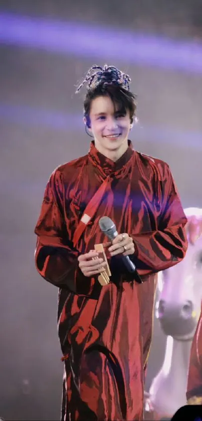 Performer in elegant red attire on stage with dark background.