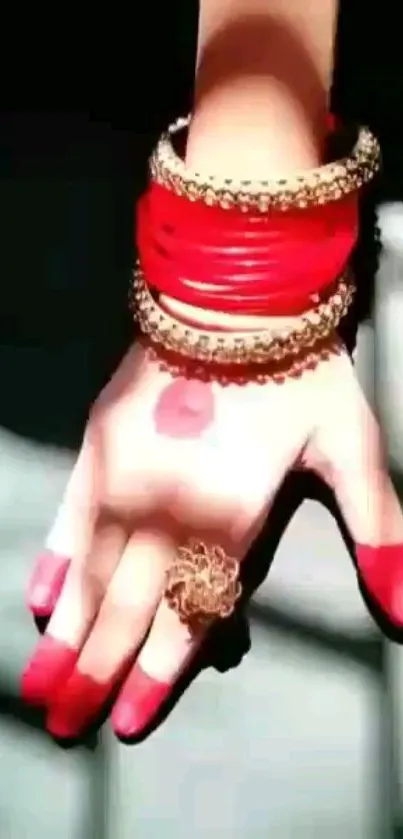 Hand wearing red bangles with intricate jewelry design.