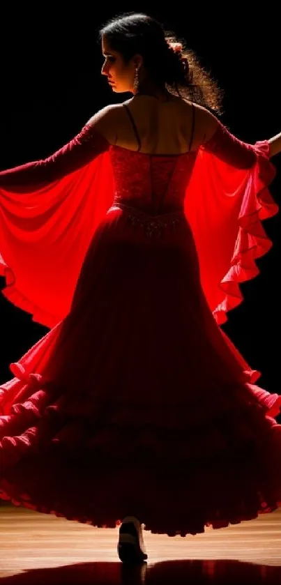 Elegant dancer in red dress on stage, illuminated and graceful.