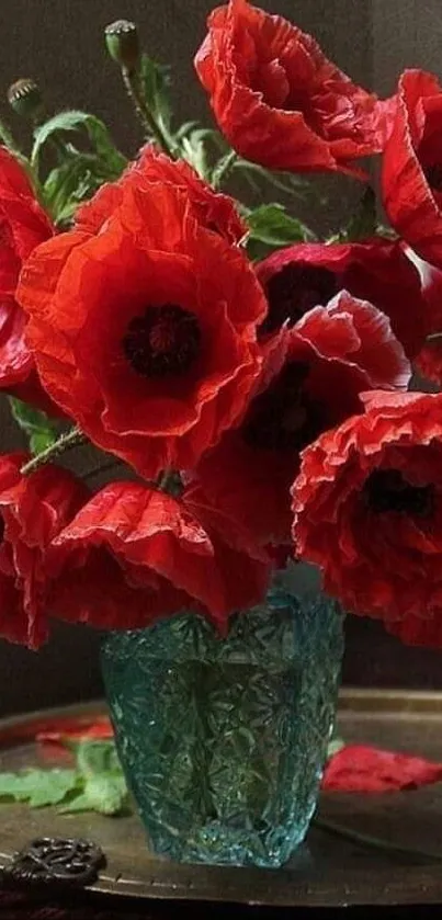 Red flowers in a teal vase on display.