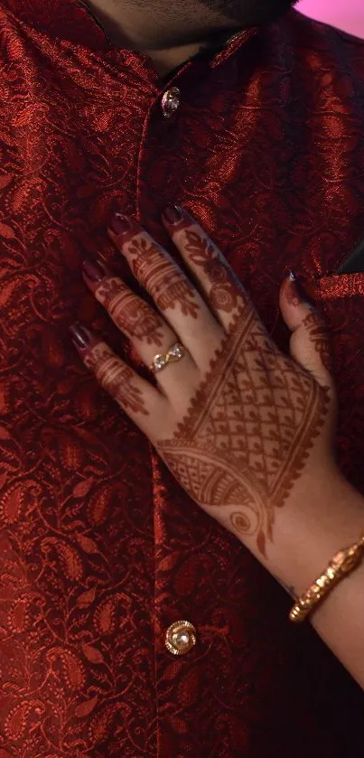 Intricate mehndi design on hand with red fabric background.