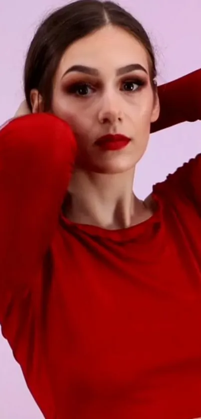 Woman in red top posing elegantly against a light pink background.