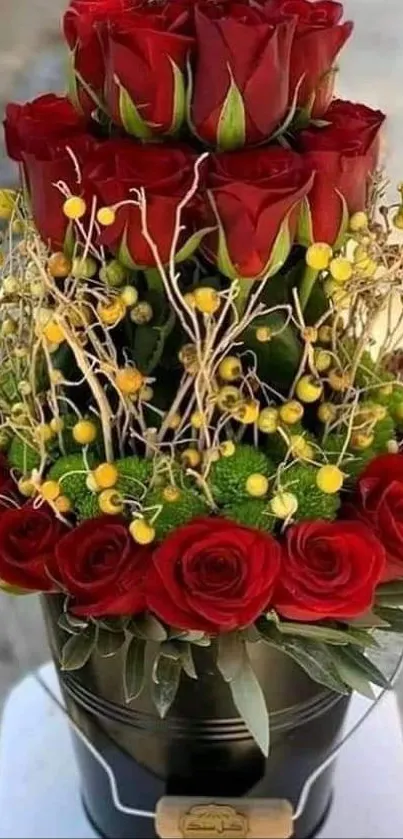 Elegant bouquet of red roses with yellow accents in a black bucket.