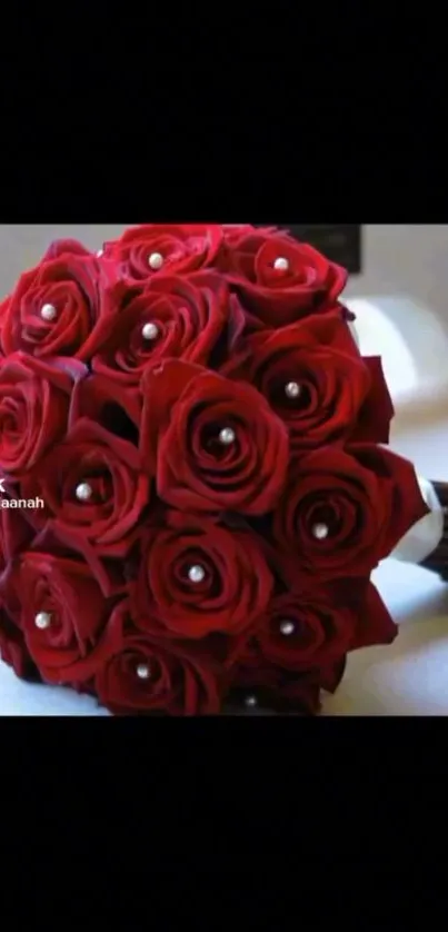 Elegant bouquet of red roses with pearl accents on a dark background.