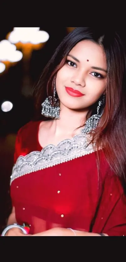 Woman in elegant red saree, posing gracefully.