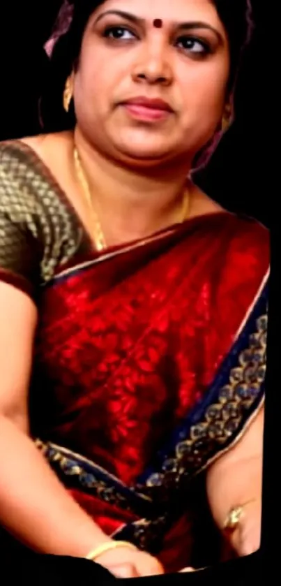 Woman wearing a red saree on dark background.