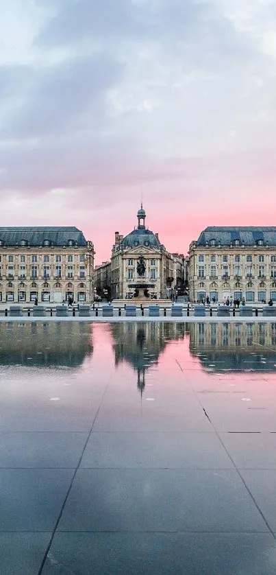 Majestic cityscape with reflective water under a pastel pink sky at sunset.