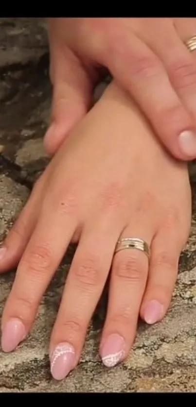 Hands with rings on rustic background, symbolizing elegance.