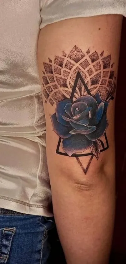 Arm tattoo with blue rose and geometric patterns.