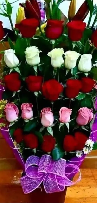 Vibrant bouquet of red, white, and pink roses with a purple bow.