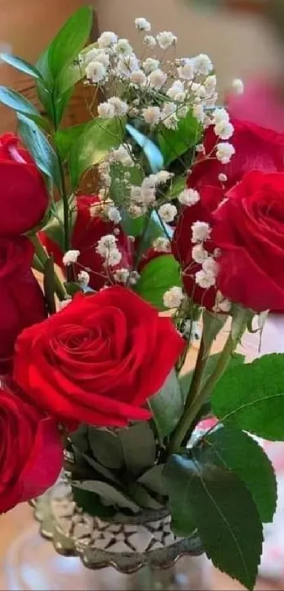 Vibrant bouquet of red roses with green leaves in a clear vase.