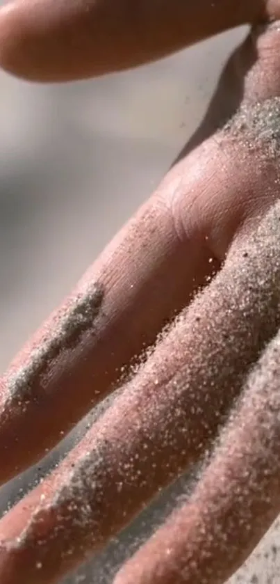 A hand gracefully dusted with sand, creating a serene natural texture.