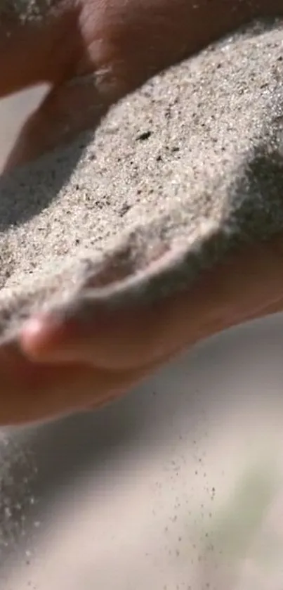 Hand holding flowing sand in serene image.