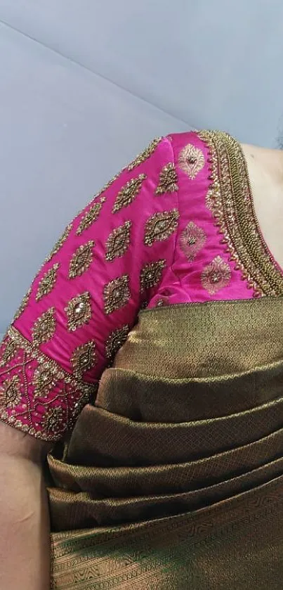 Close-up of a pink and green saree with intricate patterns.