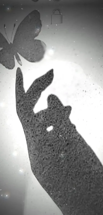 A black and white silhouette of a hand reaching towards a butterfly.