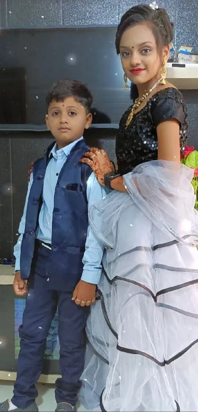 Elegant siblings in dance attire pose in a stylish room.