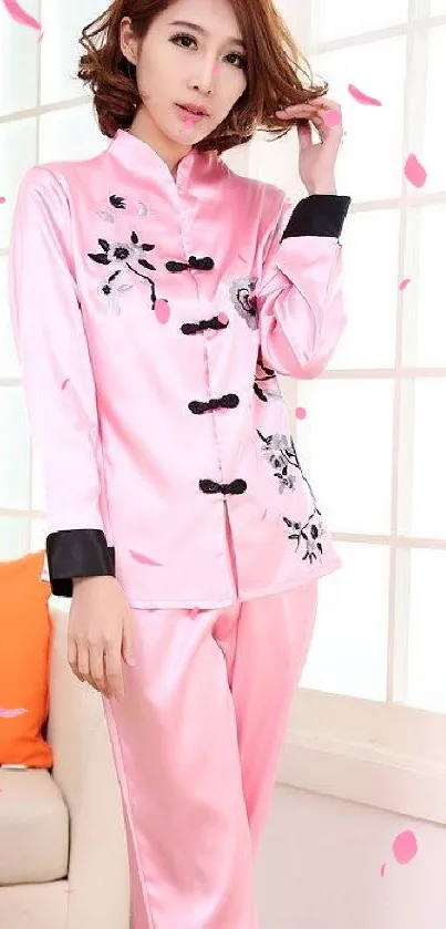 Woman in pink silk pajama set with elegant design.