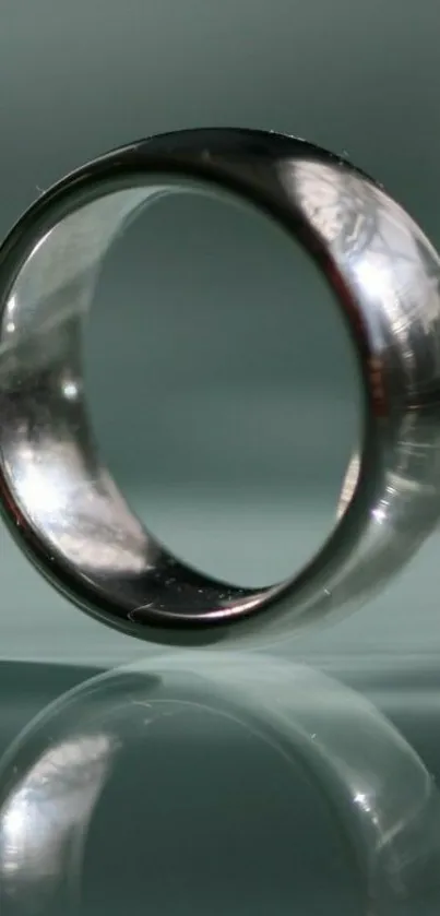 Elegant silver ring with reflection on teal background.