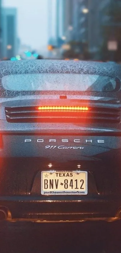 Porsche 911 Carrera in the rain with city lights in the background.