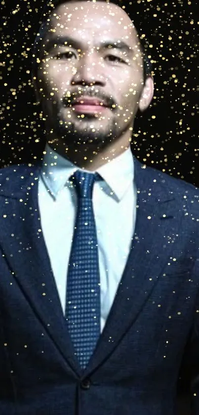 Man in a navy blue suit with glittering gold particles on a dark background.