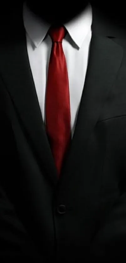 Elegant black suit with a red tie on a dark background.